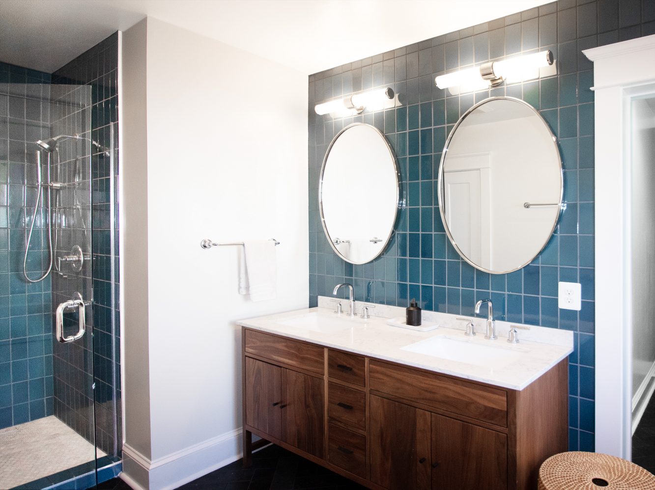 Interior view of primary bath shown mid-century modern, double sink mahogany vanity, "Heath Ceramics" tile and nickel finish hardware.