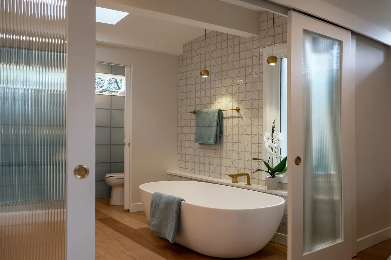 interior image of primary bath showing retracted glass doors. 